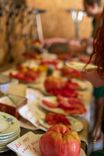 Masă cu diverse roșii, feluri de mâncare și un dovleac mare în prim-plan.
