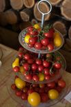 Three-tiered etagere with red and yellow tomatoes against a wooden background.