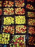 Diferite soiuri de mere stivuite în cutii la o piață.